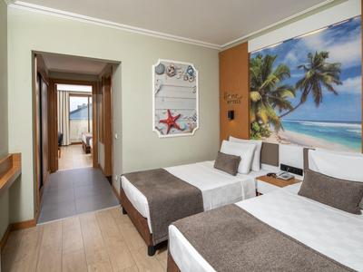 Hotel room with two single beds, nautical wall art, and modern decor.