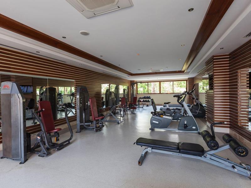 Modern gym with various workout machines and a large wall mirror.
