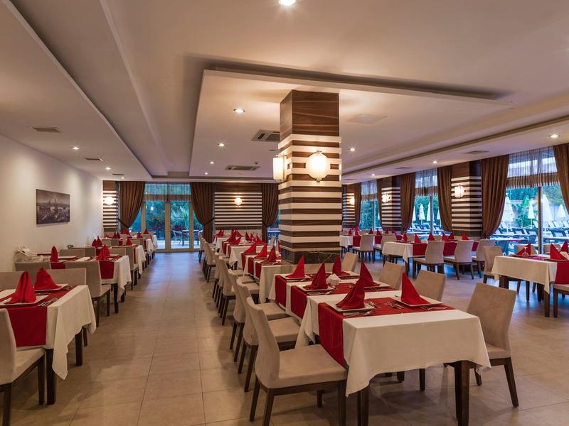 Large dining room with tables, white tablecloths, and red napkins in a hotel.