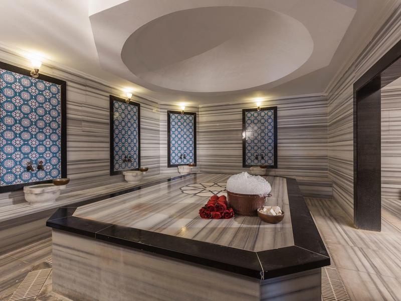 Luxurious bathroom with large marble bed, decorative windows, and circular ceiling accent.