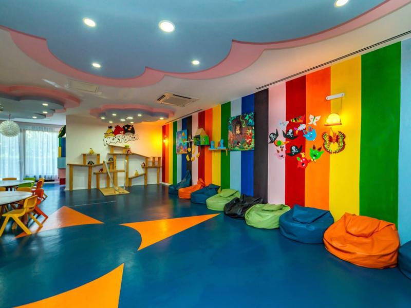 Colorful children's playroom with bean bags, toys, and a wooden table in a hotel.