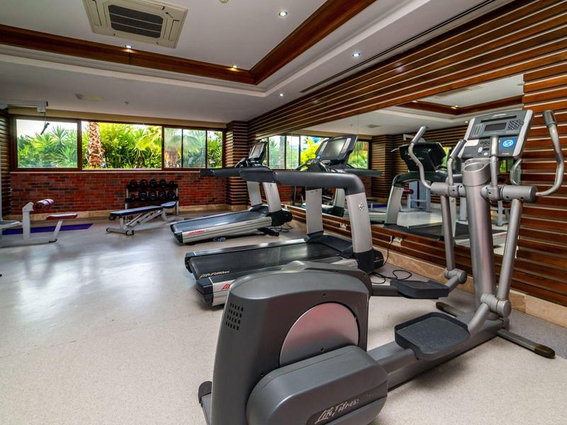 Brightly lit hotel gym with treadmills and strength training equipment.