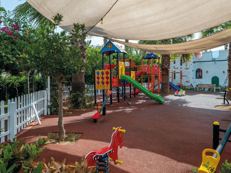 A colorful children's playground with slides and swings under a sunshade.