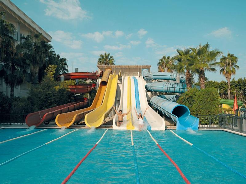 Multiple water slides end in a large blue pool under sunny skies.