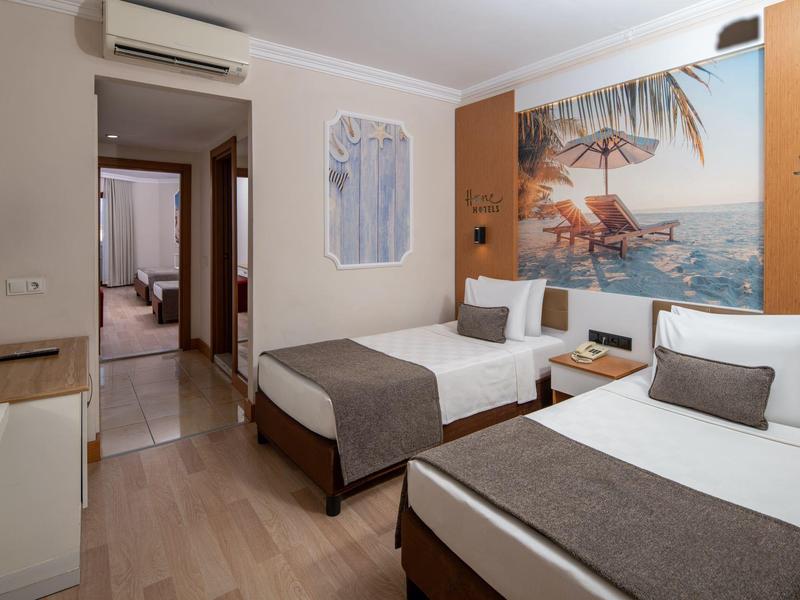 Hotel room with two single beds, wooden floor, and a beach-themed wall painting.