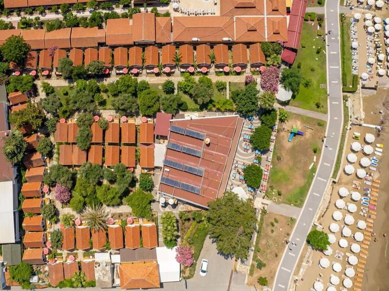 Aerial view of a beach resort with orange-roofed buildings and beachfront umbrellas.