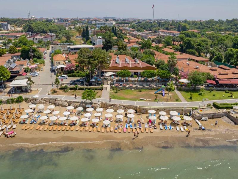 Aerial view of a beach with sunbeds and umbrellas along a shoreline near a coastal resort.