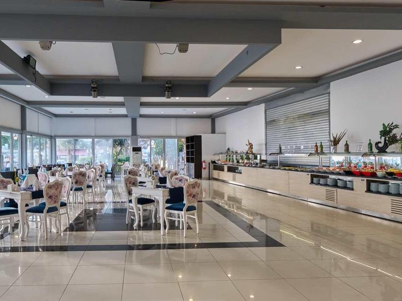 Spacious hotel dining area with large windows, modern furniture, and buffet setup.