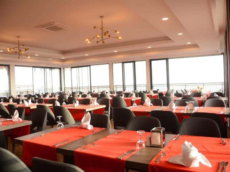 Sala da pranzo luminosa e moderna con tovaglie rosse e grandi finestre con vista.