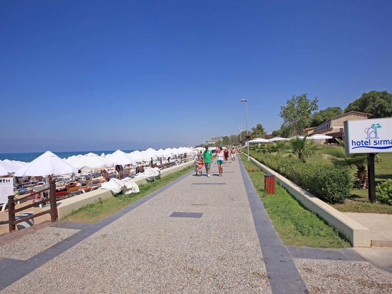 Passeggiata con lettini e ombrelloni vicino al mare in una giornata di sole.