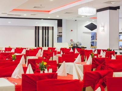 Ristorante elegante con sedie rosse e tavoli apparecchiati di bianco in un ambiente moderno.