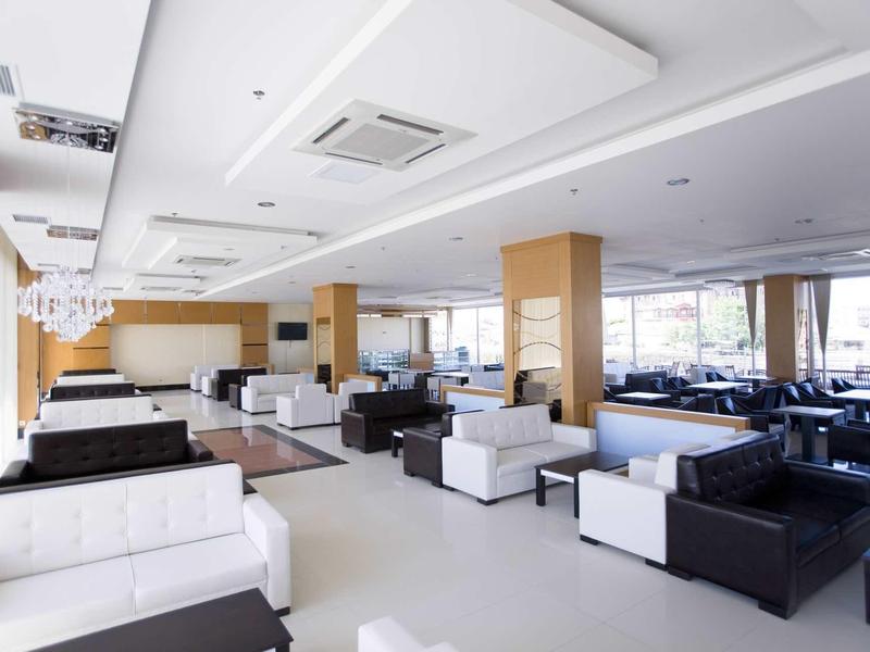 Lounge d'hotel moderna e luminosa con divani bianchi e neri e grandi finestre.