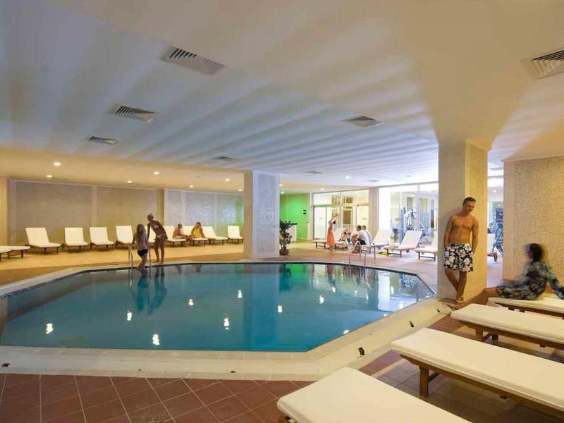 Piscina coperta con lettini e ospiti in un'atmosfera rilassata da hotel