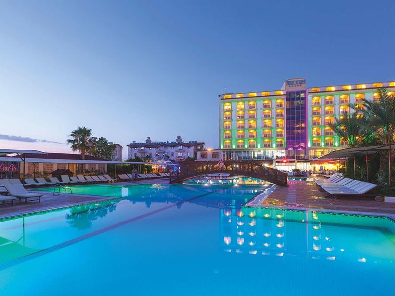 Hotel illuminato con piscina e lettini al tramonto