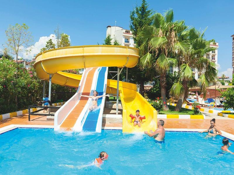 Parco acquatico con grandi scivoli d'acqua, piscina e palme verdi sullo sfondo.