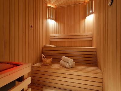 Interior view of a wooden sauna with benches, towels, and a wooden bucket.