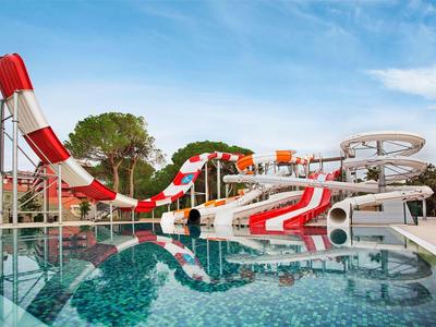 Colorful water slide complex next to a clear pool under a blue sky.