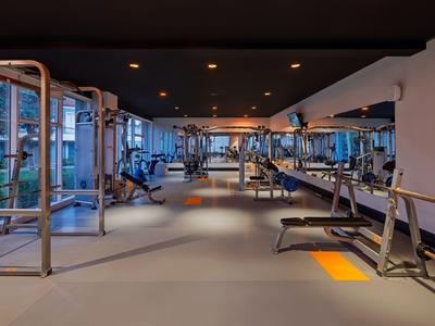 Moderner Fitnessraum mit Trainingsgeräten und großen Fenstern mit Blick ins Freie.