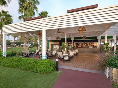 Open dining area with tables, chairs, and lamps in a tropical hotel setting.
