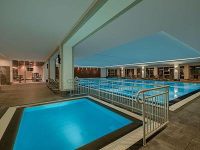 Innenbereich eines Hotels mit zwei beleuchteten Schwimmbädern und modernem Design.