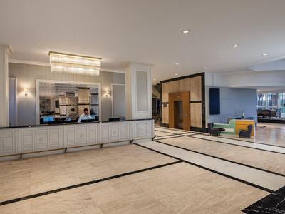 Spacious modern hotel lobby with light walls, large reception desk, and lounge area.