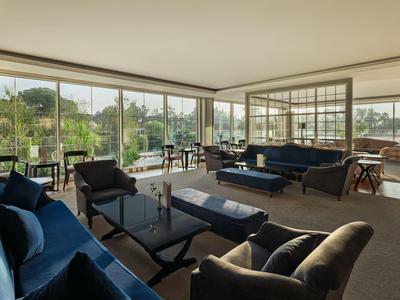Spacious, bright living area with blue sofas and floor-to-ceiling windows overlooking nature.