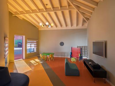 Bright lounge area with table, chairs, TV, gaming table, and modern lighting.