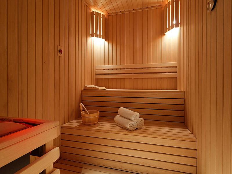Interior view of a wooden sauna with benches, towels, and a wooden bucket.