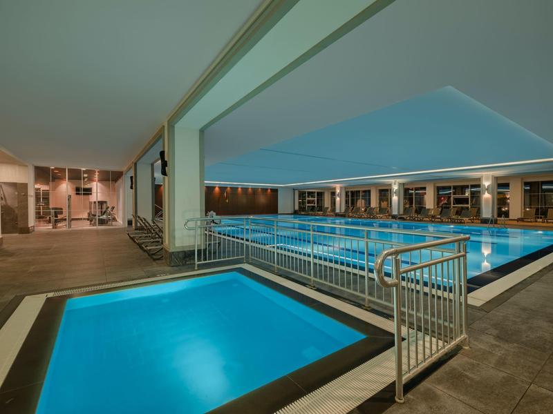 Indoor pool with adjacent hot tub in a modern hotel area with comfortable seating.