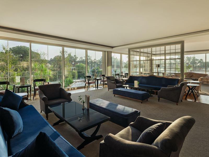 Spacious, bright living area with blue sofas and floor-to-ceiling windows overlooking nature.