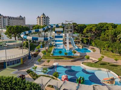 Water park with large water slides and swimming pools in front of hotel buildings amid greenery.