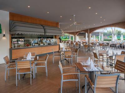 Outdoor restaurant with wooden tables and chairs in a tropical hotel.