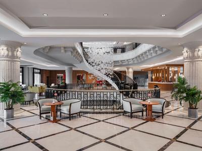 Hotel lobby with curved staircase, comfortable seating areas, and elegant columns.