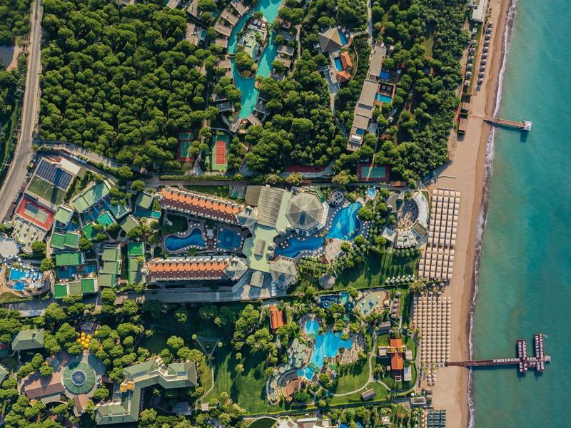 Aerial view of a resort with multiple pools, buildings, and a beach by the sea.