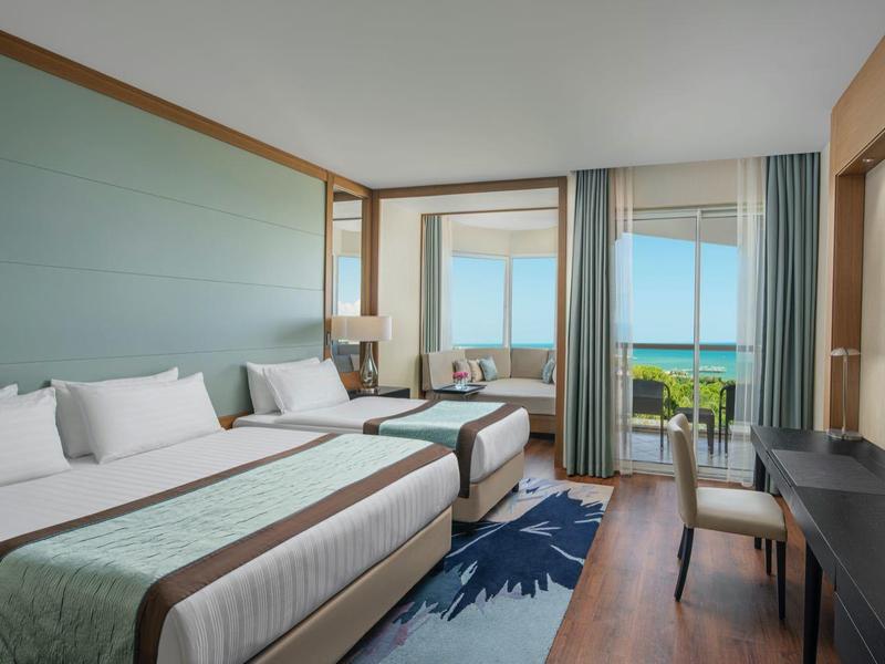 Modern hotel room with double bed, balcony, and sea view.