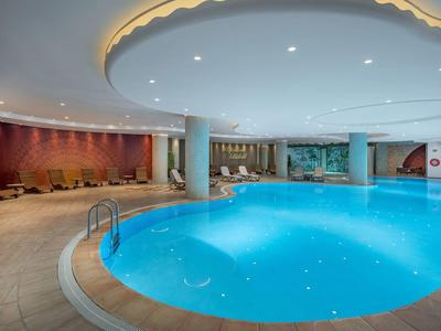 Indoor pool with round shape, lighting, and seating area in a modern hotel.