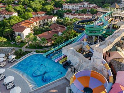 Water park with slides and pool next to hotel with gardens and seating areas
