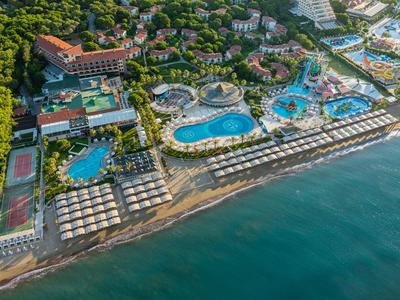 Aerial view of a beachfront resort with multiple pools and lush green gardens.