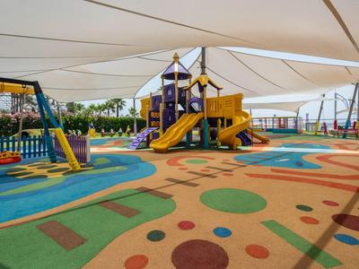 Covered colorful children's playground with slides and swings on soft flooring.