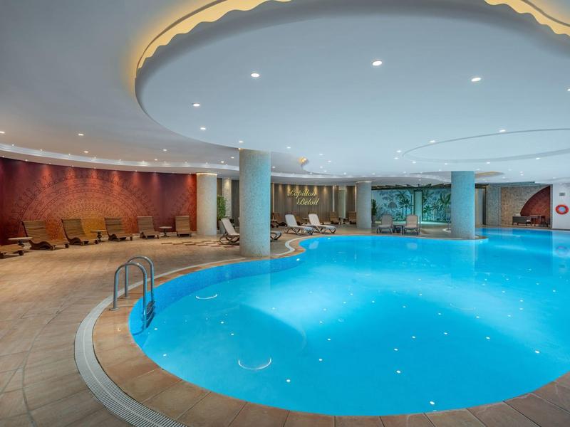 Indoor pool with round shape, lighting, and seating area in a modern hotel.