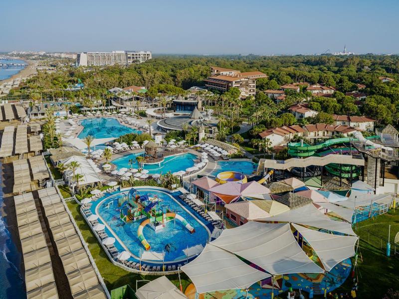 Large water park by the sea with pools, water slides, and sun umbrellas at a holiday resort.