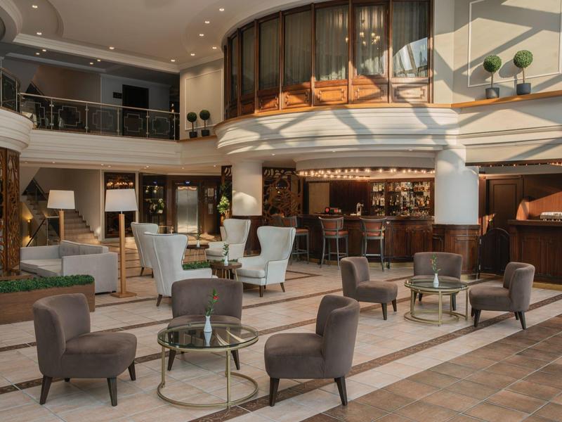 Spacious hotel lobby with comfortable armchairs and modern reception area under natural light.