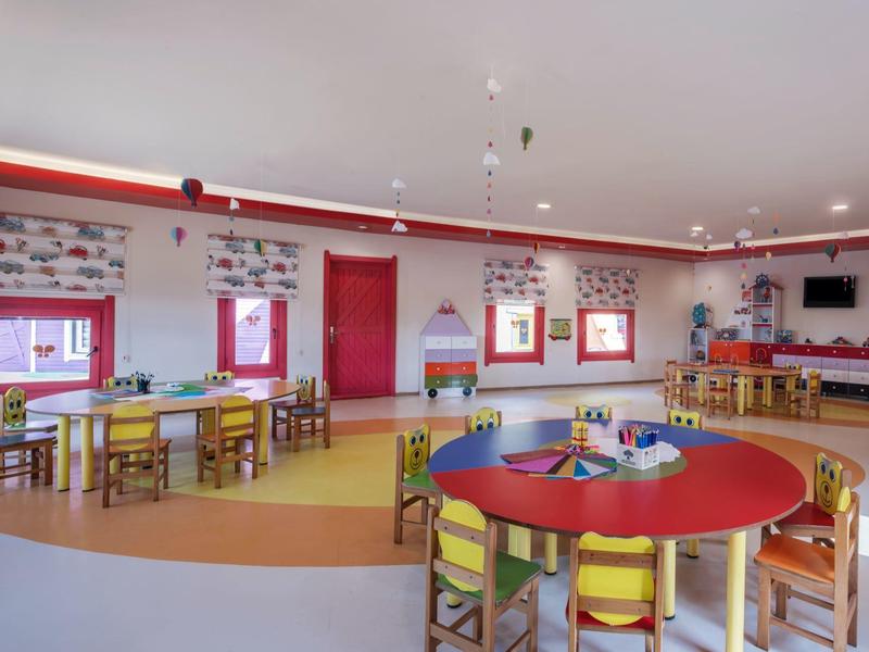 Colorful children's playroom with small tables and chairs in a brightly lit room.
