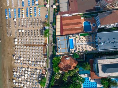 Vista aérea de un hotel con piscina y playa con tumbonas junto al mar.