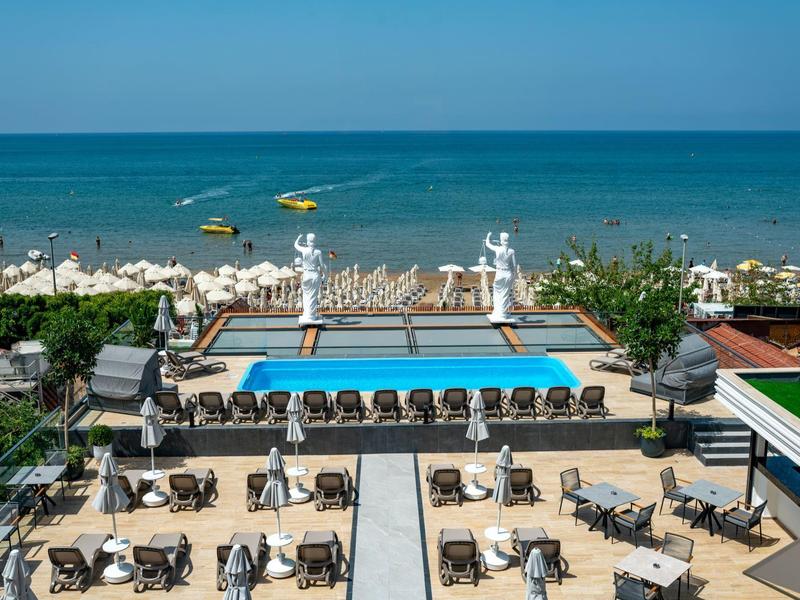 Área de piscina del hotel con tumbonas y vista al mar en el fondo.