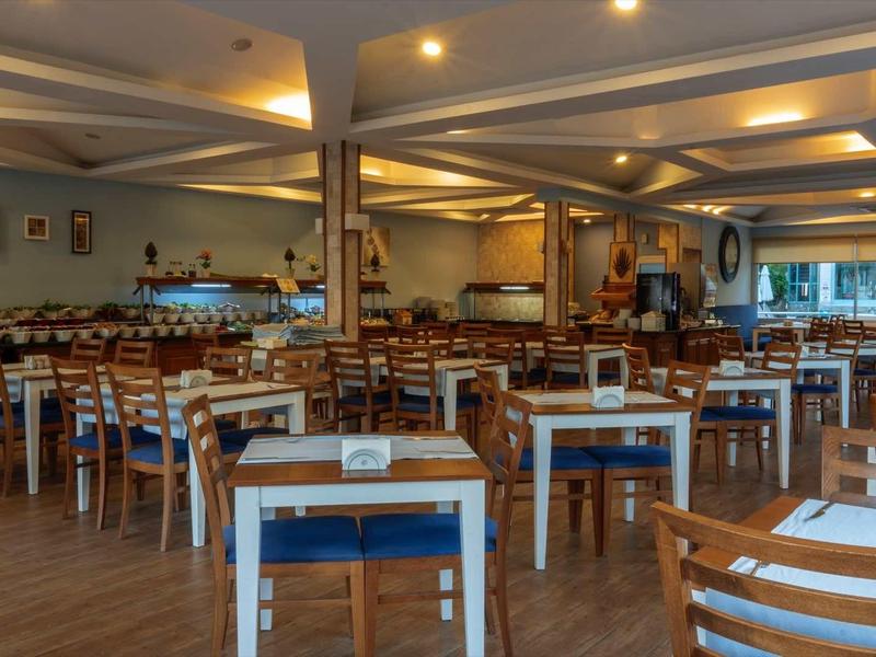 Großer, heller Speisesaal mit vielen Holztischen und -stühlen, modernem Design und warmem Licht.