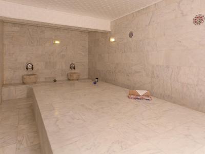 Locale hammam minimalista con pareti in marmo e ampia area centrale per stendersi.