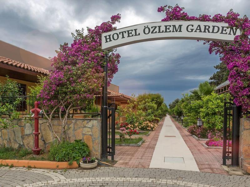 Entrance gate to a hotel with bougainvillaea plants and a long path to reception.