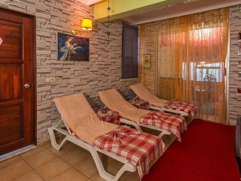 Interior area with three lounge chairs, checkered blankets, and a wooden door beside a stone wall.