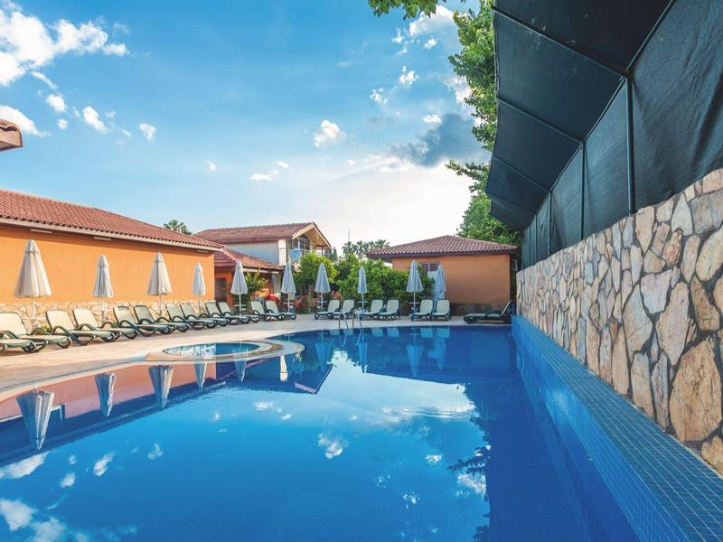 Inviting hotel pool with lounge chairs and umbrellas under a blue sky.